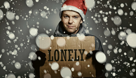 Mann steht im Schnee und hält Pappschild mit der Aufschrift "Lonely" hoch